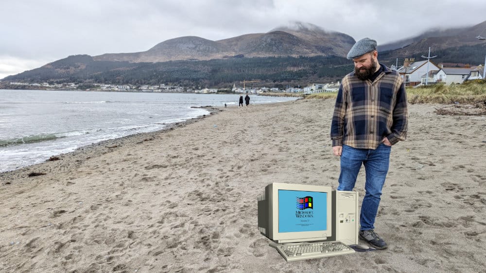 a photo of me walking on a beach on a cloudy day looking down at a superimposed old Windows PC