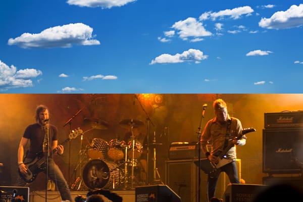 the top half of this image is a cropped photo of a blue sky with some clouds in it. the bottom half is a shot of the band, Mastodon, playing live